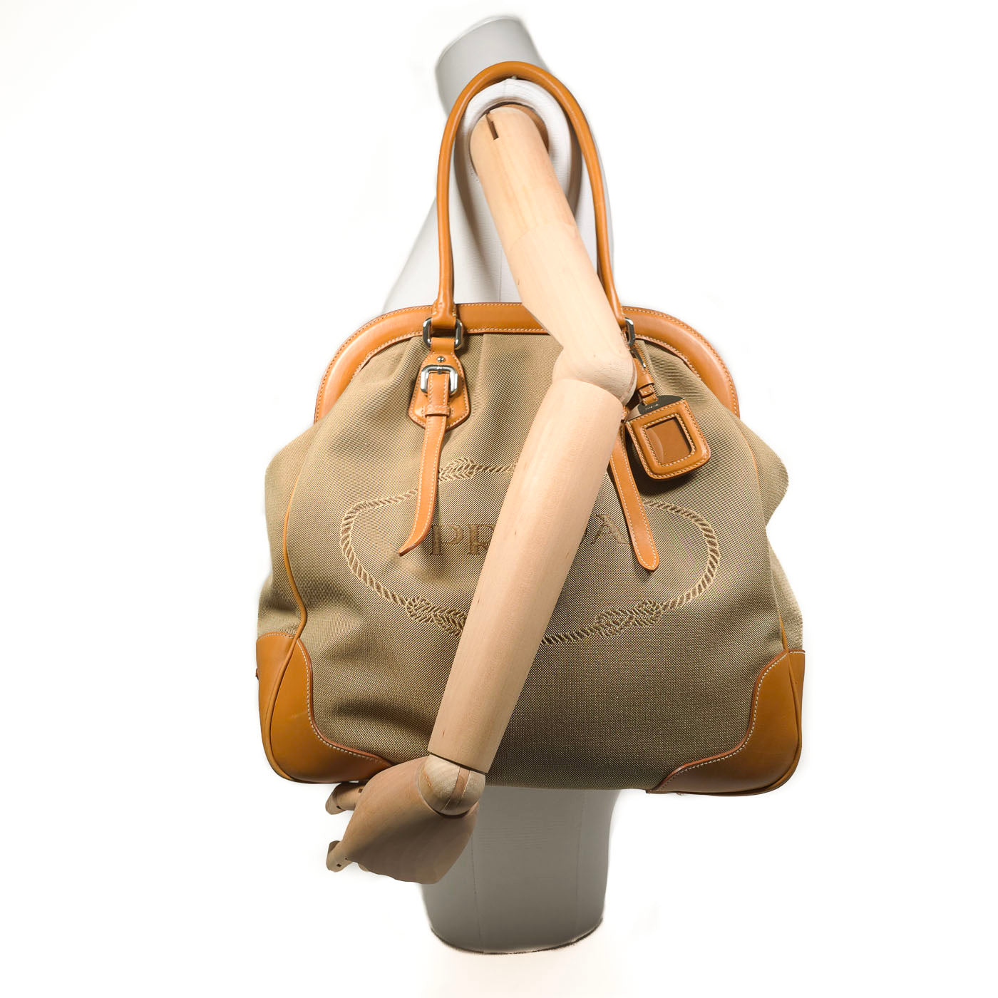 Prada tote bag with logo jacquard canvas and leather handles, displayed on a mannequin.
