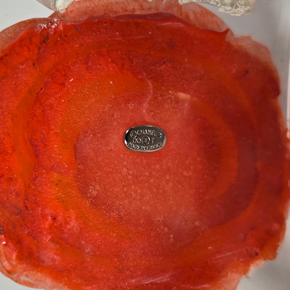 A vintage Chanel coral camellia flower lucite resin cuff bracelet displayed on a black box with the Chanel brand visible, y2k.