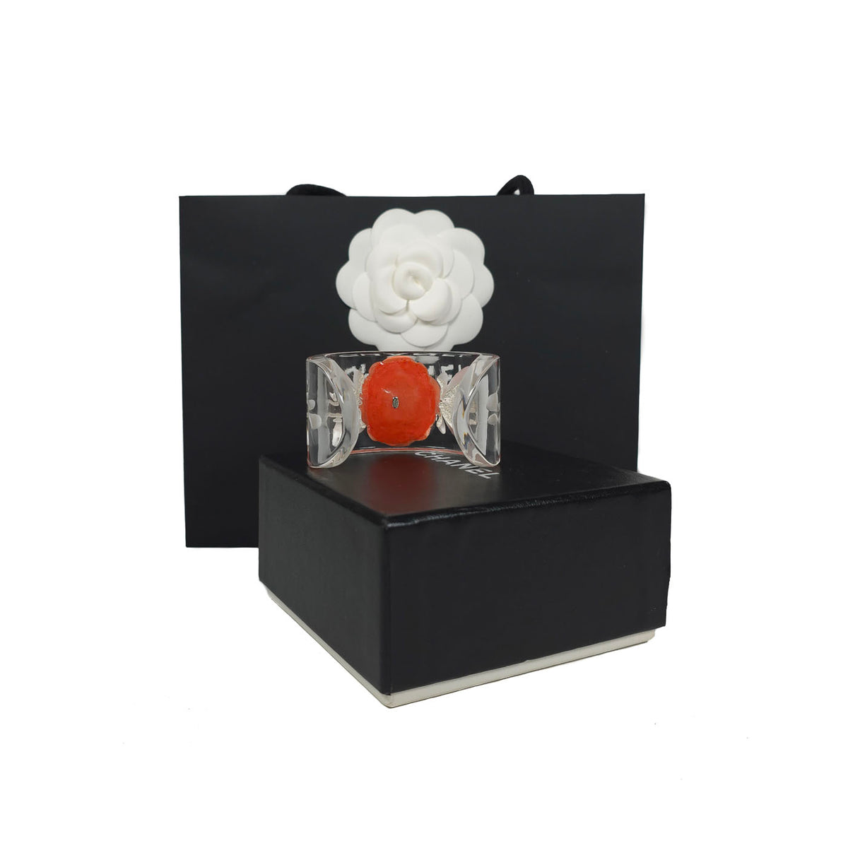 A vintage Chanel coral camellia flower lucite resin cuff bracelet displayed on a black box with the Chanel brand visible, y2k.