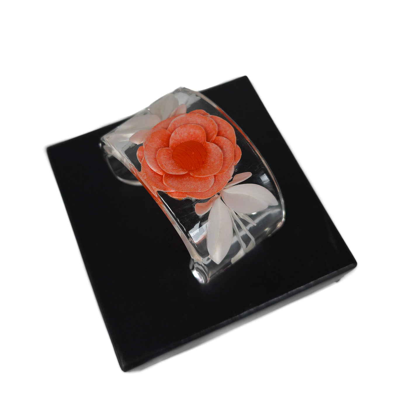 A vintage Chanel coral camellia flower lucite resin cuff bracelet displayed on a black box with the Chanel brand visible, y2k.