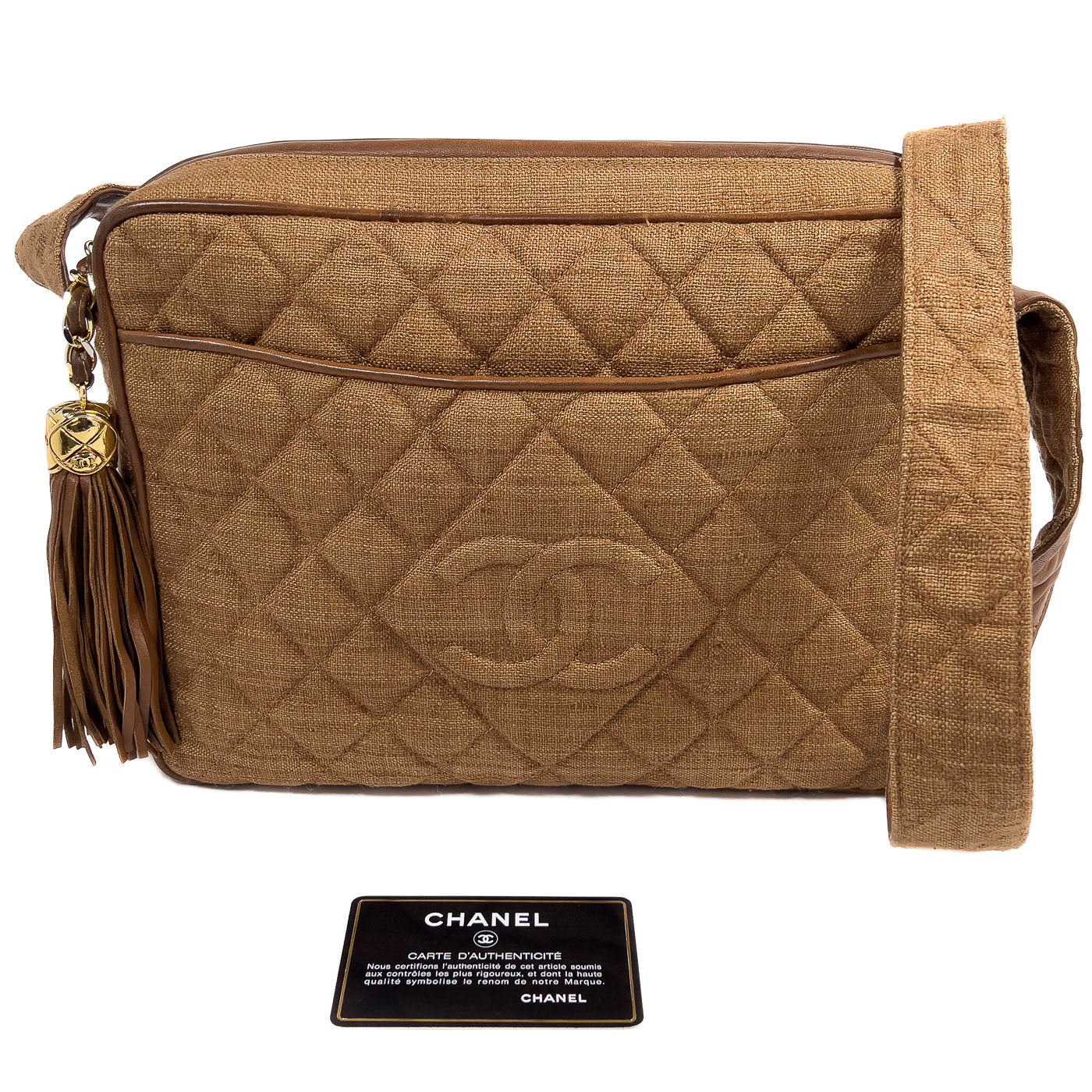 A vintage Chanel camera bag in camel brown with a quilted design, large stitched CC logo, and a tassel.