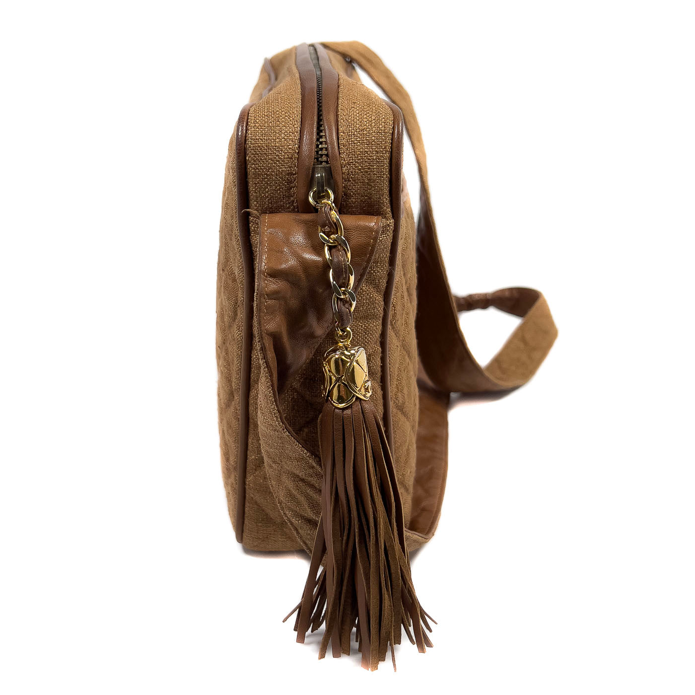 A vintage Chanel camera bag in camel brown with a quilted design, large stitched CC logo, and a tassel.