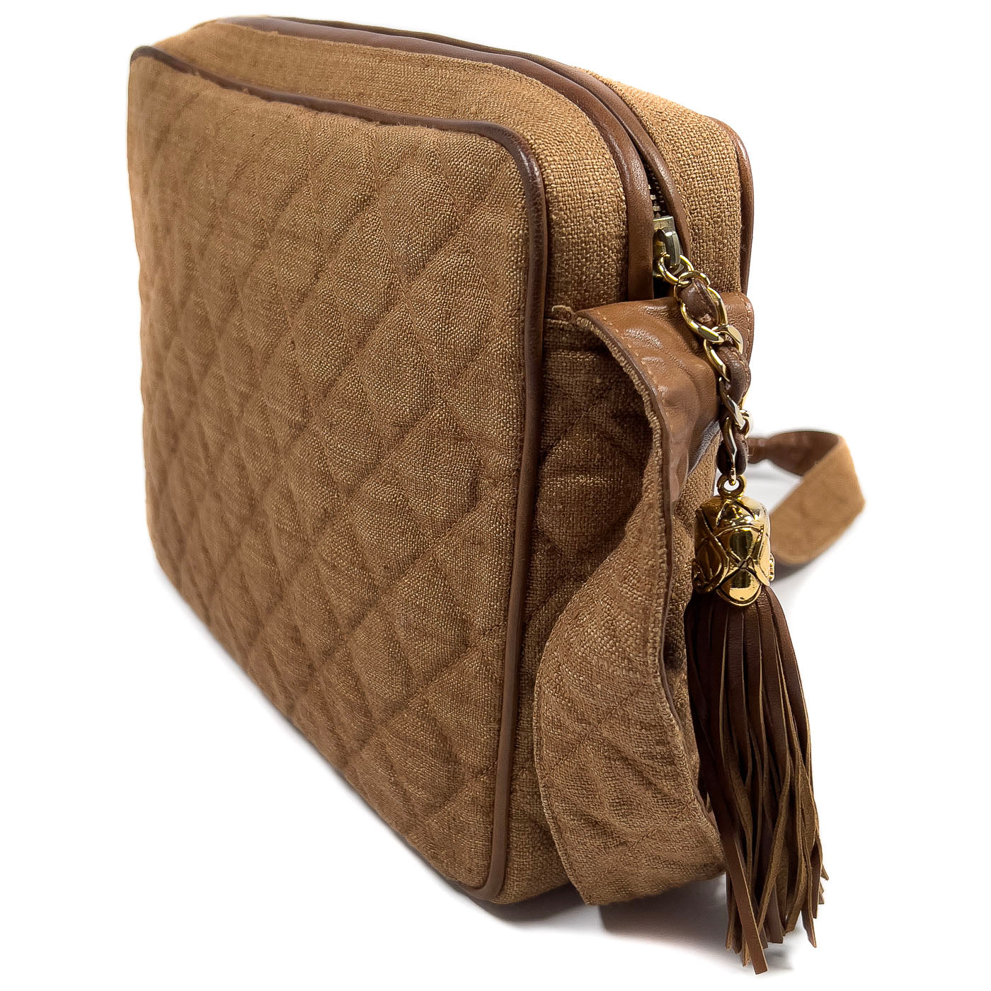 A vintage Chanel camera bag in camel brown with a quilted design, large stitched CC logo, and a tassel.