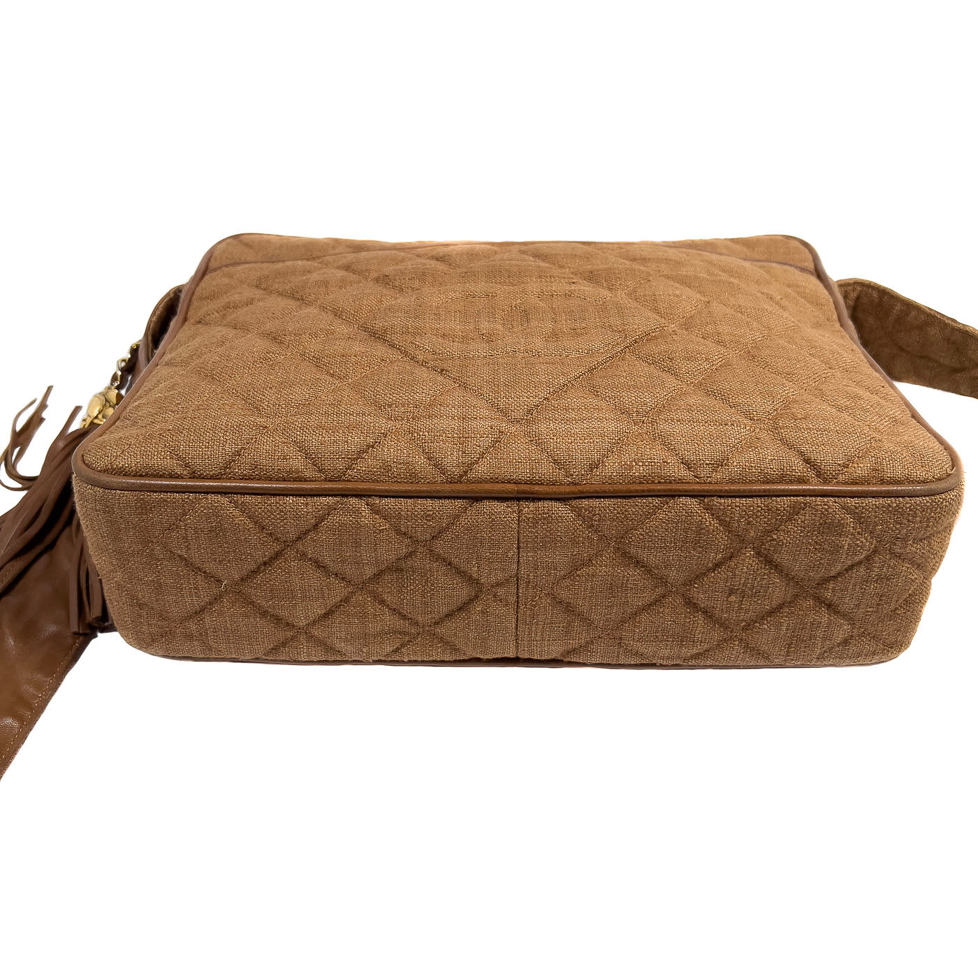 A vintage Chanel camera bag in camel brown with a quilted design, large stitched CC logo, and a tassel.