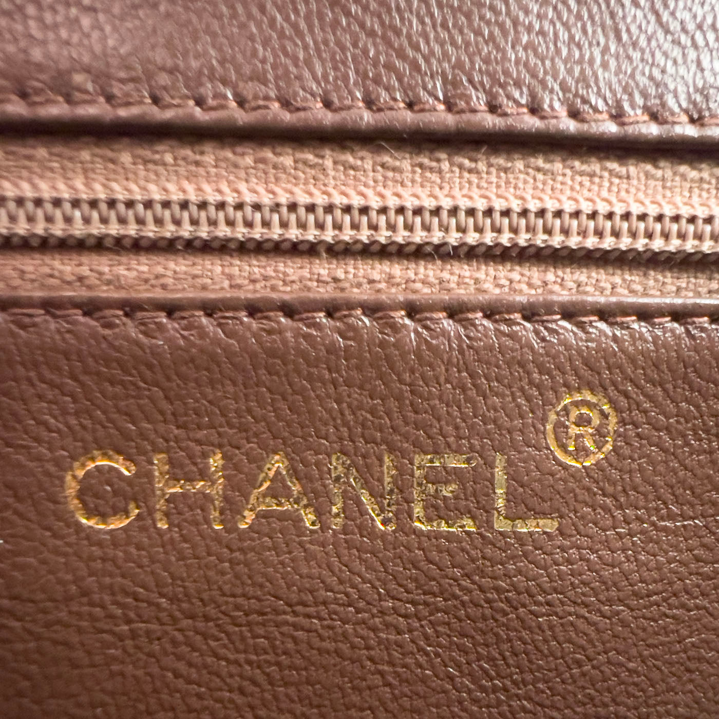 A vintage Chanel camera bag in camel brown with a quilted design, large stitched CC logo, and a tassel.