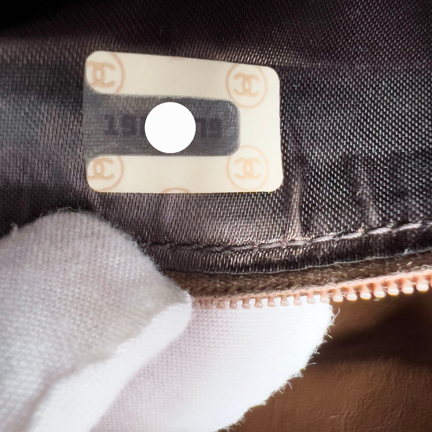 A vintage Chanel camera bag in camel brown with a quilted design, large stitched CC logo, and a tassel.