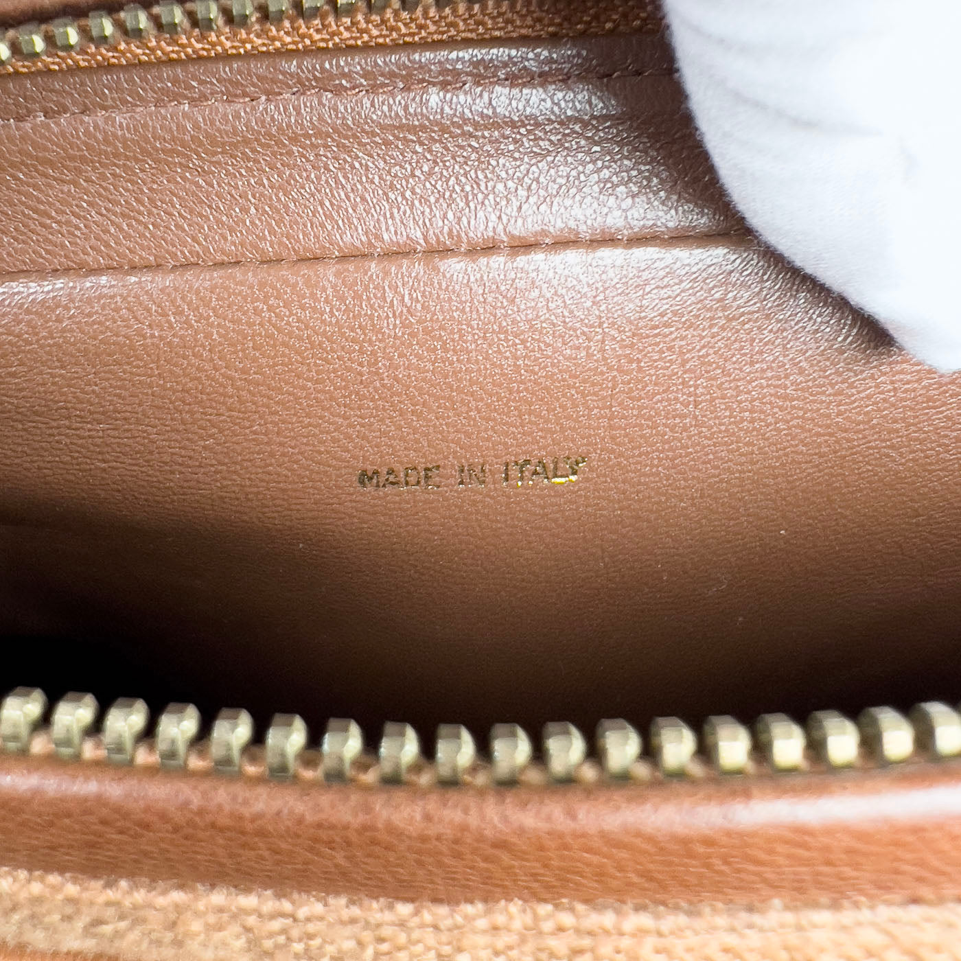 A vintage Chanel camera bag in camel brown with a quilted design, large stitched CC logo, and a tassel.