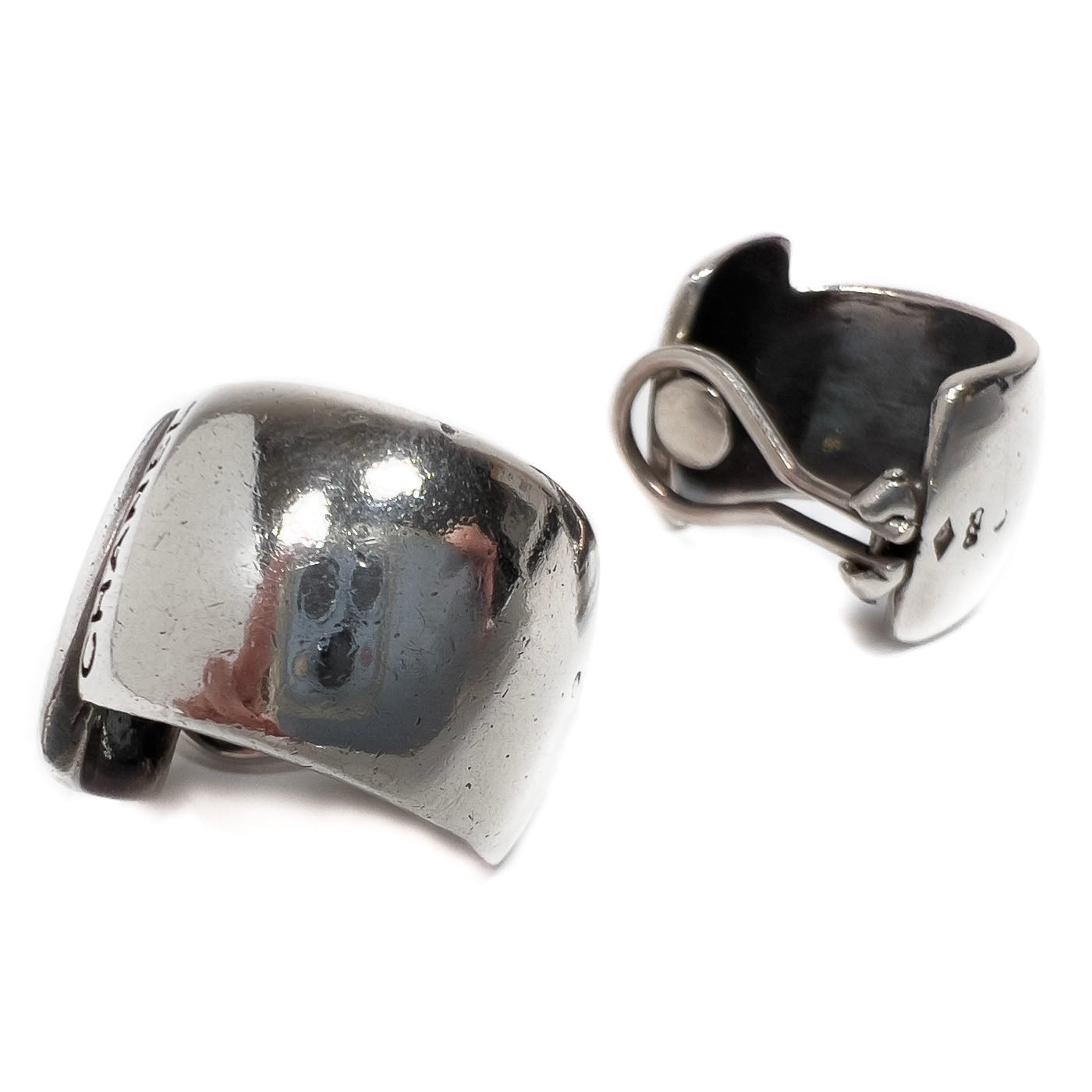 A pair of vintage Chanel sterling silver clip earrings with a sleek, curved wraparound design.
