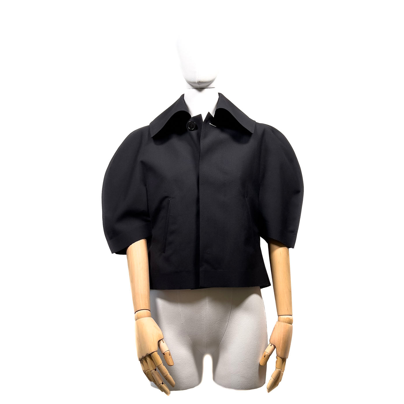 Comme des Garçons Jacket JUNYA WATANABE Black JPN M.
A black short cape jacket with a mandarin collar and short sleeves, displayed on a mannequin.