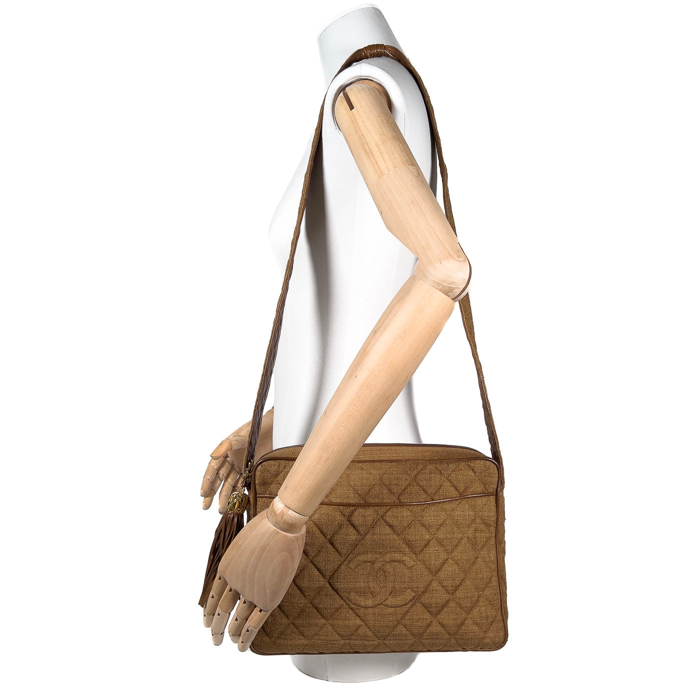 A vintage Chanel camera bag in camel brown with a quilted design, large stitched CC logo, and a tassel.